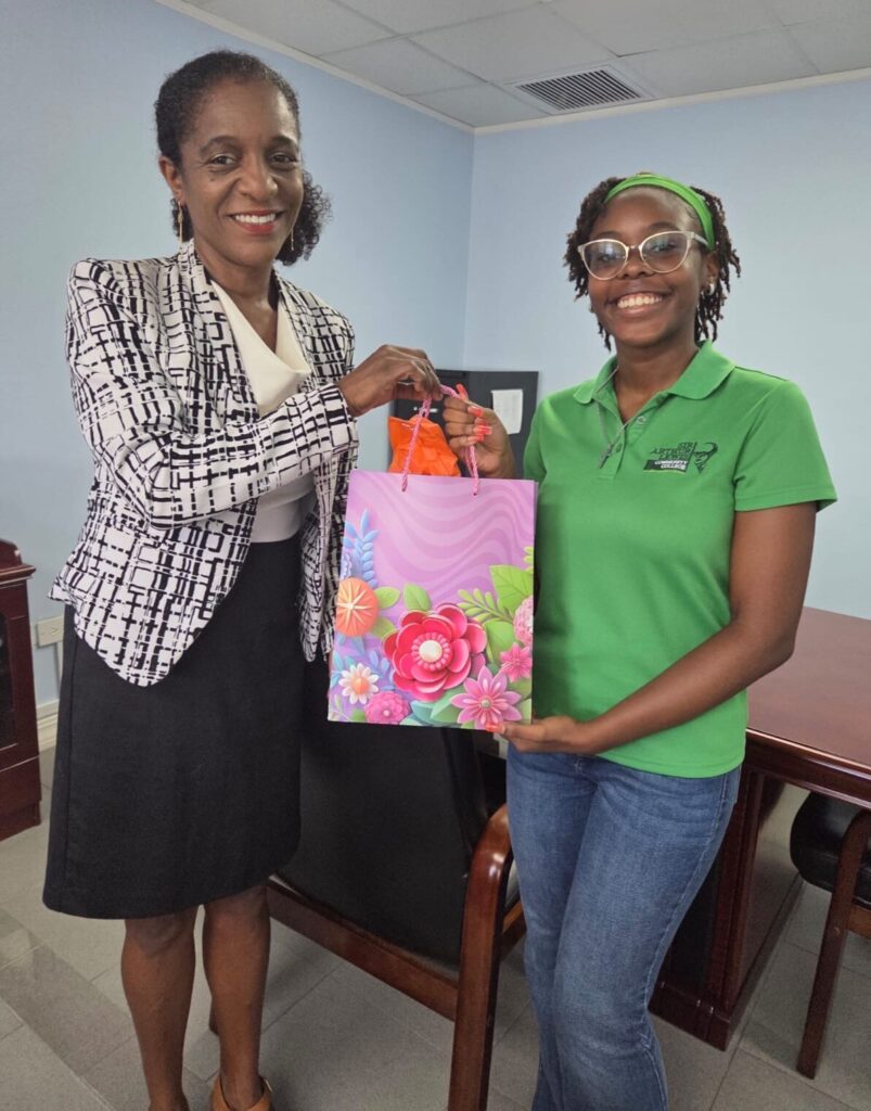 Khloe Charles receiving a token of appreciation from Permanent Secretary Josette Maxwell-Dalsou